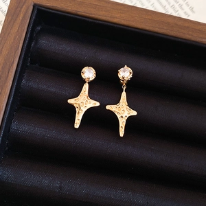 Macro detail of gold-plated star earrings with zircon inlay on black velvet display
