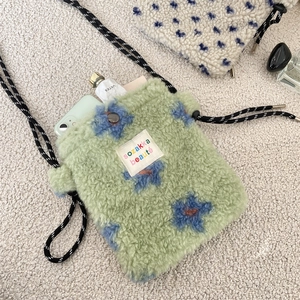 Detail view of plush crossbody bag with green faux shearling and floral pattern decoration