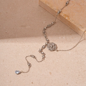 Elegant silver flower necklace with zircon waterdrop pendant on textured stone background