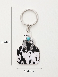 Detailed view of western style keychain with cow print tag and turquoise horseshoe pendant