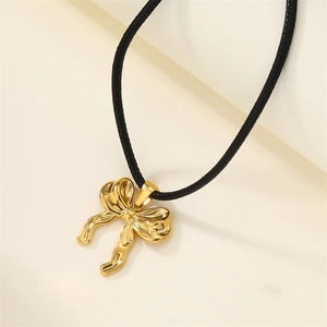 18k gold plated stainless steel bow necklace on a black wax cord over soft geometric background