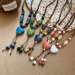 Vue détaillée de pendentifs cœur en céramique et de perles bohèmes tissées main