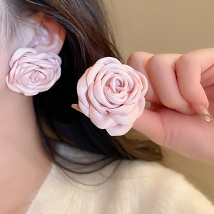 Close-up of model wearing pink mesh fabric rose earrings with pearl accents
