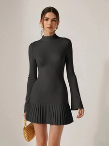 Detail view of the fine pleated skirt and slim fit flared long sleeves of the black dress