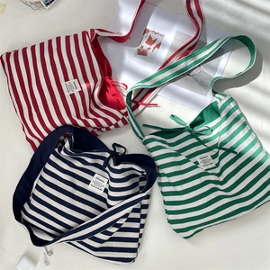 Flat lay of striped canvas tote bags in red, green, and blue with lifestyle props