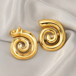 Boucles d'oreilles spirales en acier titane doré sur un tissu élégant en soie grise