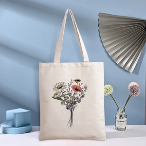 Minimalist daisy canvas tote bag with floral print on light blue background studio setting