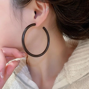 Close-up of model wearing large black minimalist acrylic round hoop earrings