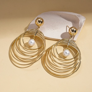 Detailed view of golden multi-layer geometric hoop earrings with a white pearl accent