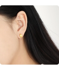 Close-up of golden oval matte earrings with brushed texture on ear model