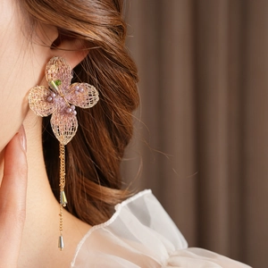 Detailed shot of vintage pink and gold knitted flower earrings with long beaded tassels