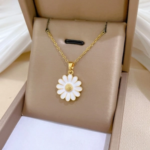 Macro detail of daisy flower pendant with white enamel petals on a gold chain