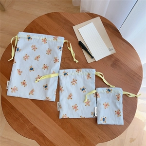 Three sizes of blue striped cotton drawstring bags with bear print on a wooden table