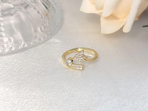 Macro detail of gold-tone star ring with micro-pave crystals on white silk background