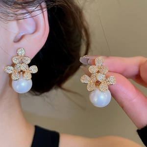 Detailed view of an elegant flower pearl earring with zircon petals worn on the ear