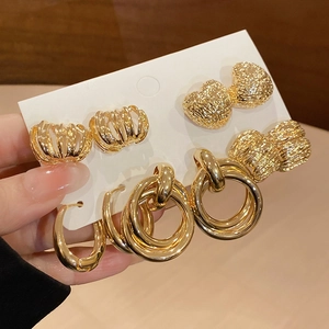 Detail of three gold earrings featuring heart, textured, and triple ring designs