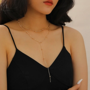 Detail of double-layer gold necklace with square pendant and delicate bead accents