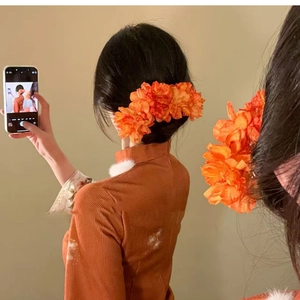 Detail of vibrant orange fabric floral hair pin styled on a retro Chinese updo