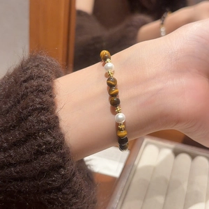 Close-up of vintage tiger eye stone and pearl beaded bracelet on a wrist