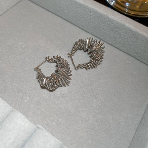 Detail view of silver spiky geometric hoop earrings resting on a grey velvet jewelry tray