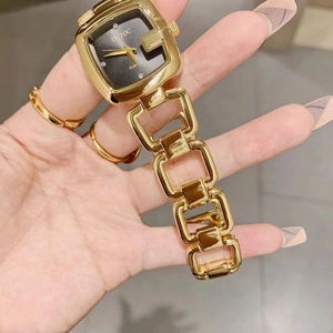Macro view of gold square quartz watch with metal chain strap and black dial on wrist