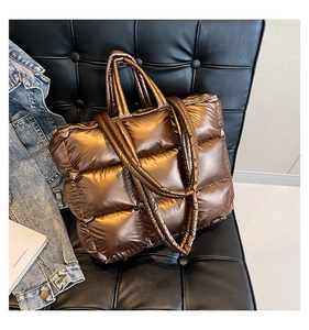 Dettaglio della borsa puffer metallizzata trapuntata con finitura lucida e ampi manici