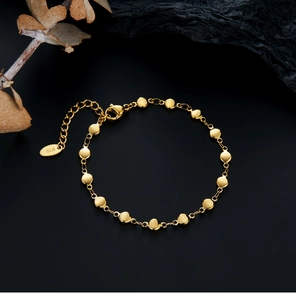 Detailed macro view of 18K gold plated heart and disc link bracelet with K18 hallmark tag