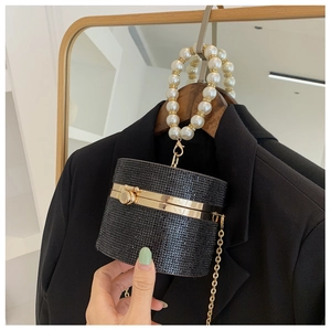 Detail of black rhinestone cylinder evening bag with white pearl handle and gold chain