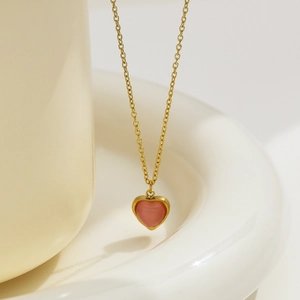 Elegant gold titanium necklace featuring a soft pink heart pendant on a minimalist background
