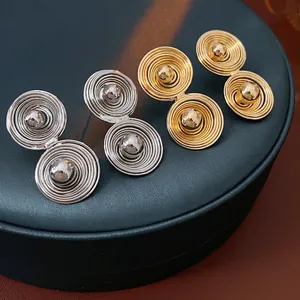 Minimalist spiral metal stud earrings in gold and silver finish with polished center ball