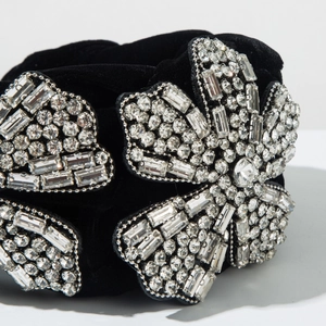 Détail de motifs floraux en strass argentés sur un serre-tête en velours noir épais