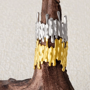 Detailed view of gold and silver irregular flow texture open rings on wooden base