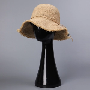 Detailed close-up of khaki straw sun hat with woven tassel brim and decorative cord