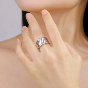 Detailed view of silver wide band ring with multi-layer grooves worn on finger