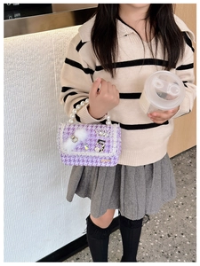 Detail of purple houndstooth girls' mini bag with pearl handle and cute charms