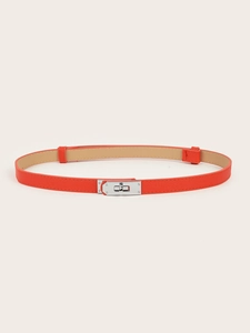 Detail shot of orange slim leather belt featuring a silver metal buckle and cross texture
