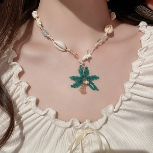 Detail einer handgefertigten Perlenkette mit Kokosnuss-Anhänger und echten Muscheln
