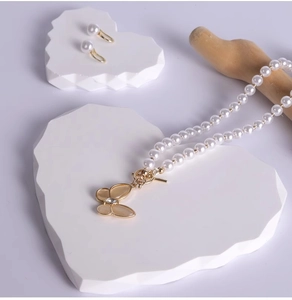 Detailed macro view of pearl necklace with gold butterfly pendant on stone display
