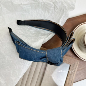 Close-up of blue denim bow headband with yellow contrast stitching on white paper