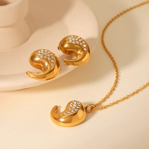 Gros plan détaillé du pendentif et des boucles d'oreilles dorés sertis de pierres zircons