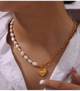 Detailed close-up of a pearl and gold chain necklace featuring a textured heart pendant