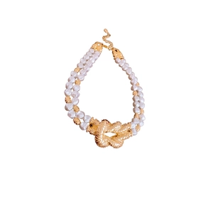 Double-layered white pearl necklace featuring a central golden metal knot pendant