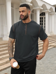 Close-up of charcoal grey polo shirt with orange contrast stitching and button placket
