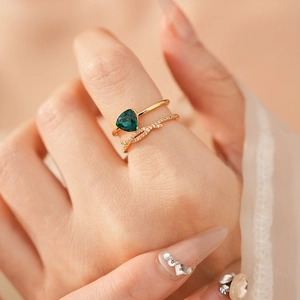 Détail de bagues plaquées or avec zircon vert triangulaire et anneau croisé pavé