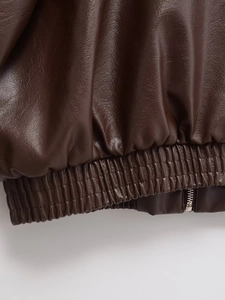 Detail of dark brown faux leather jacket featuring elastic hem and premium metal zipper