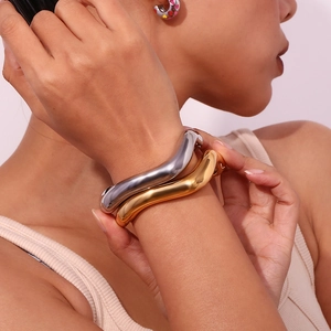 Close-up of wavy gold and silver stainless steel bangles with polished mirror finish
