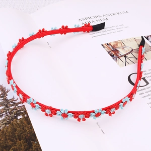 Detailed view of red floral headband with woven daisies on a magazine background