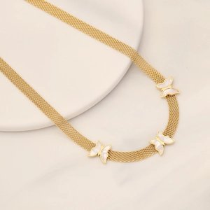 Golden mesh chain necklace with three white mother-of-pearl butterfly pendants on marble