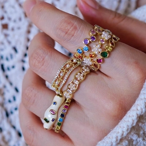 Close-up of stacked gold rings featuring colorful gems, pearls, and unique snake head design