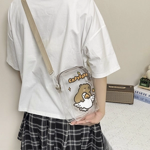 Detailed view of the clear Capybara crossbody bag with adjustable beige strap on a model